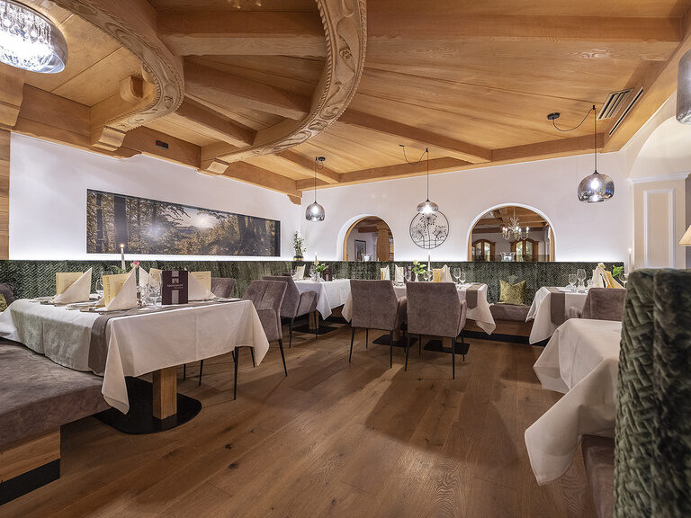 Luxuriöser Essbereich der Kaminstube des Wellnesshotels Mooshof in Bodenmais mit eleganter Tisch- und Stuhlgestaltung.