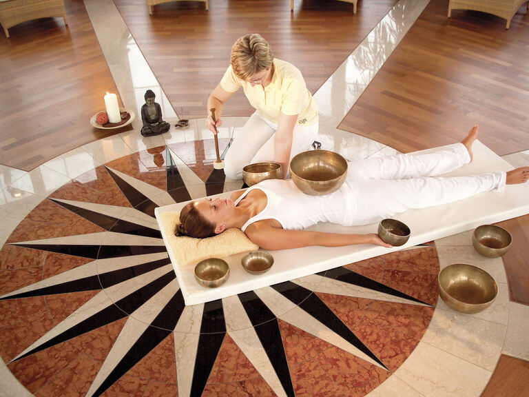 Eine Frau lässt sich bei einer Klangschalen Therapie im Wellnesshotel Mooshof in Bodenmais verwöhnen.