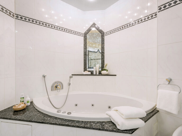 Elegantes Badezimmer mit einer großen Badewanne in der Komfortsuite des Wellnesshotels Mooshof im Bayerischen Wald.
