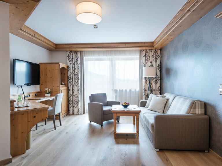 Gemütliches Wohnzimmer mit Flachbildfernseher und Couch in der Komfortsuite des Wellnesshotels Mooshof in Bodenmais.