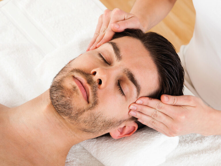 Die Nahaufnahme zeigt einen Mann bei einer verwöhnenden Kopfmassage im Spa des Wellnesshotels Mooshof im Bayerischen Wald.