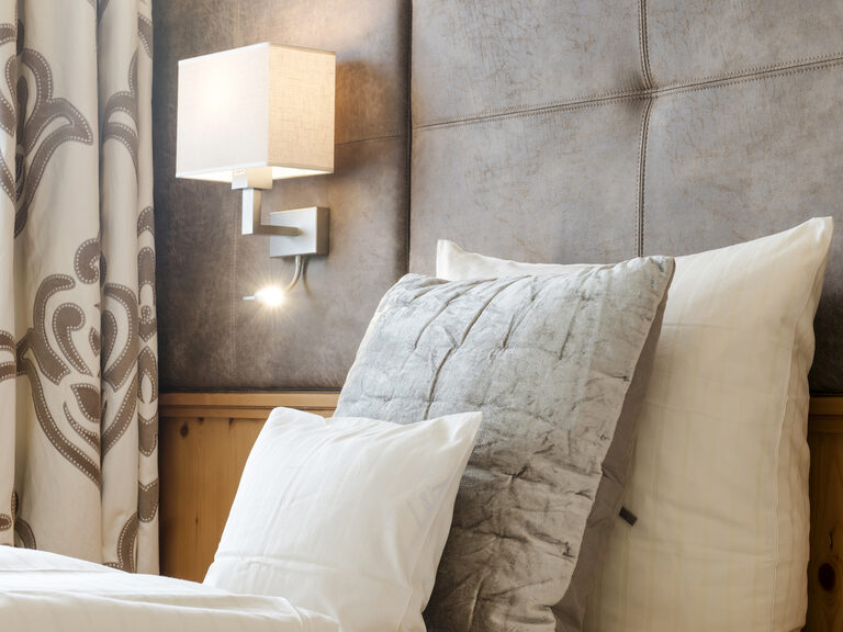 Einladendes Bett mit weißen Laken und Kissen im Landhaussuiten-Schlafzimmer des Wellnesshotels Mooshof im Bayerischen Wald.