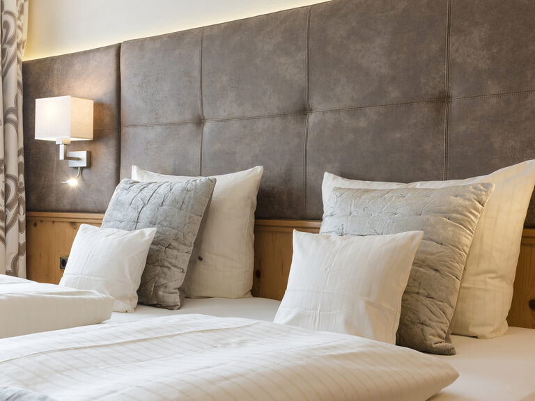 Gemütliche Betten mit weichen Textilien in den Landhaussuiten des Wellnesshotels Mooshof in Bayern laden zum Verweilen ein.