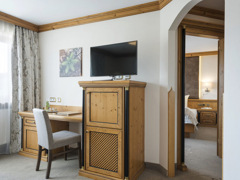 gemütliches Zimmer der Landhaussuiten im Wellnesshotel Mooshof im Bayerischen Wald mit einem Fernseher und einem modernen Arbeitstisch.
