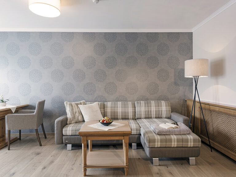 Eine gemütliche Couch und ein Sessel bilden das Herzstück des Wohnraums in der Lohwiessuite des Wellnesshotels Mooshof im Bayerischen Wald.