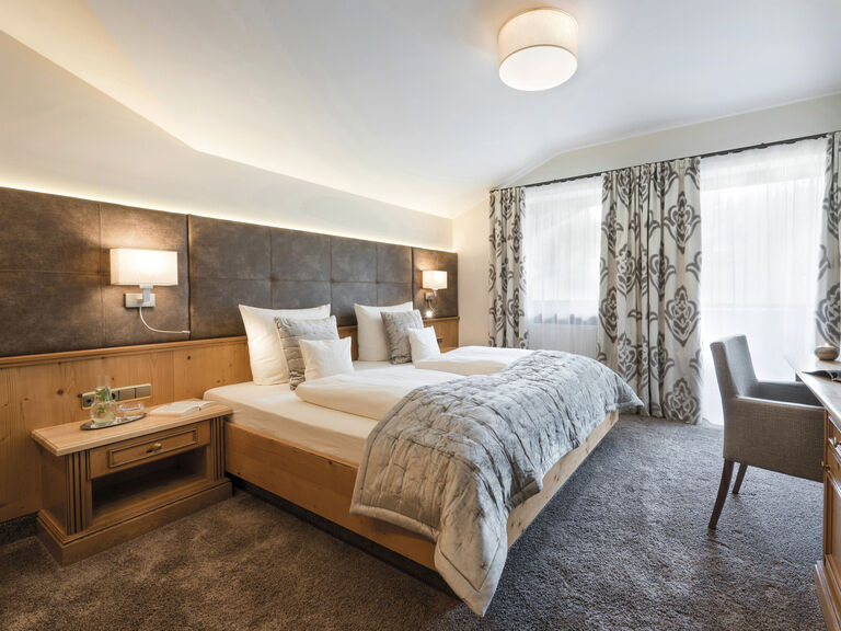 Stilvolles Zimmer in der Lohwiessuite des Wellnesshotels Mooshof im Bayerischen Wald mit bequemen Bett, Schreibtisch und Stuhl.