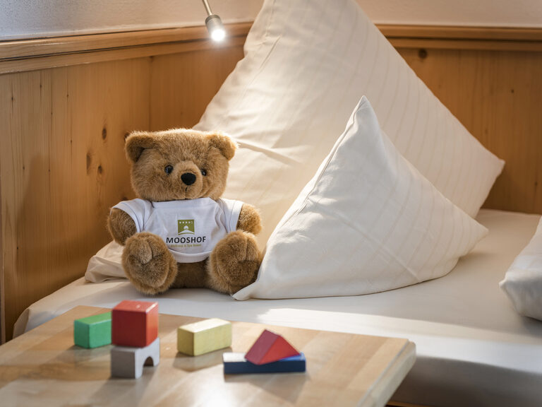 In der Lohwiessuite des Wellnesshotels Mooshof in Bayern befinden sich ein Kuscheltier und Bausteine auf dem Bett und dem Nachttisch.
