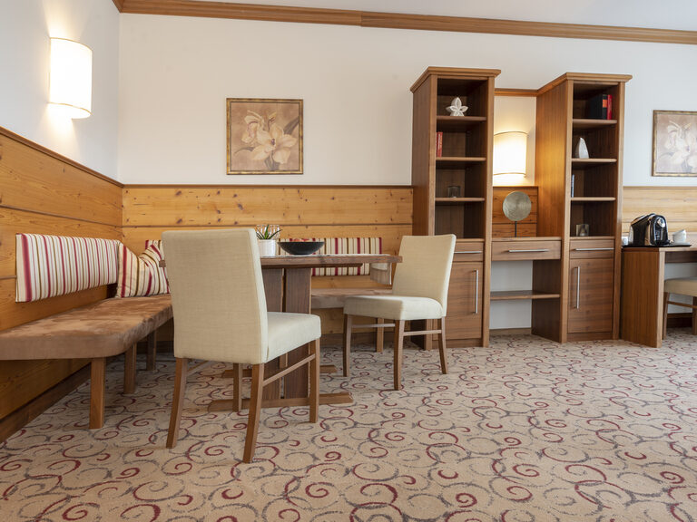 Die Erkersuite Deluxe im Wellnesshotel Mooshof in Bodenmais mit großer Sitzecke und einem modernen Schreibtisch.