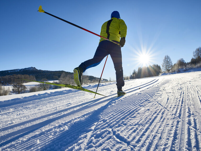 Eine Person geht beim Langlaufen einen Berg mit seinen Skiern hinauf.