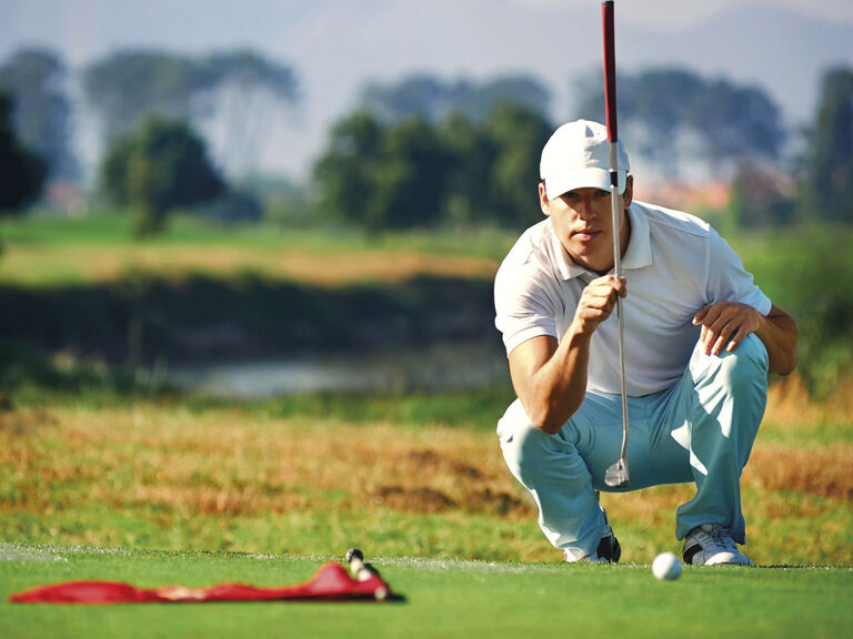 Ein Mann übt konzentriert auf einem Golfplatz