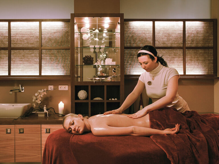 Eine Frau genießt eine entspannende Massage im Wellnessraum des Wellnesshotels Mooshof in Bodenmais.