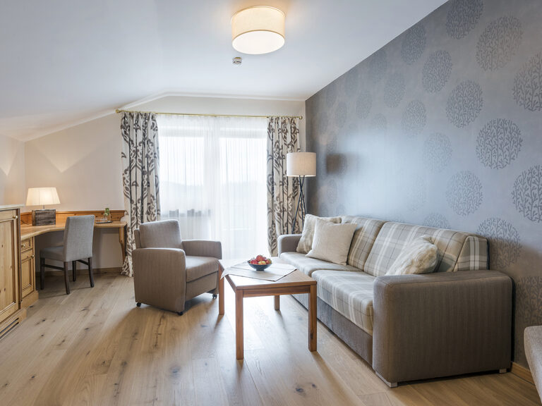 Gemütliche Wohnlandschaft mit Sofa und Fernseher – einladend und geschmackvoll dekoriert in der Silberbergsuite des Wellnesshotels Mooshof im Bayerischen Wald.