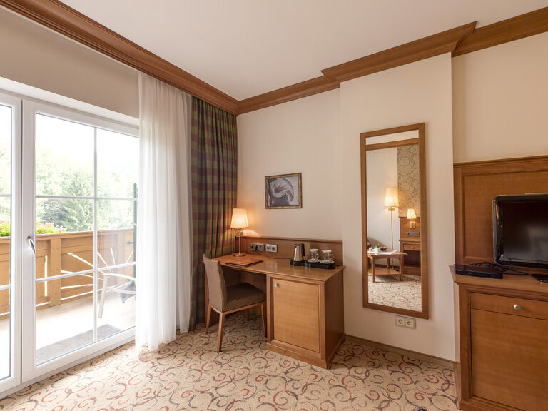 Die modern eingerichtete Single Suite im Wellnesshotel Mooshof in Bayern mit einem praktischen Arbeitsbereich in der Ecke des Ausgangs des Nordbalkons.
