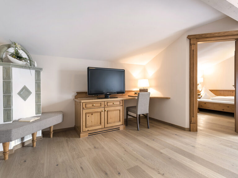 Wohnbereich der Lohwiessuite im Wellnesshotel Mooshof in Bayern mit stilvollem Holzparkettboden und moderner Unterhaltungselektronik.