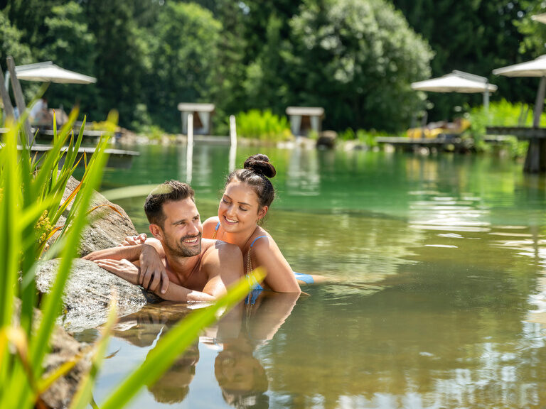 Ein Paar genießt sommerliche Stunden in einem Naturbadesee im Resort Mooshof im Bayerischen Wald.