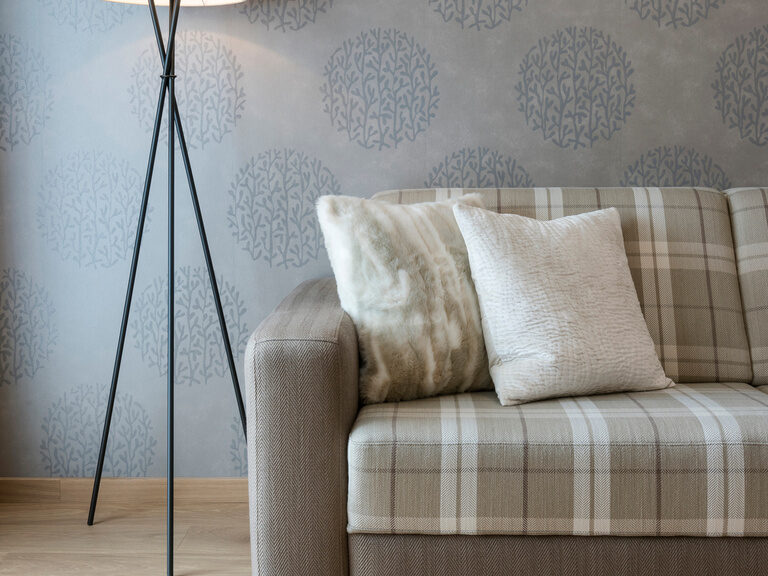 Ein Sofa mit eleganter Beleuchtung in der Panoramasuite, eingerichtet für entspannte Stunden im Wellnesshotel Mooshof im Bayerischen Wald.