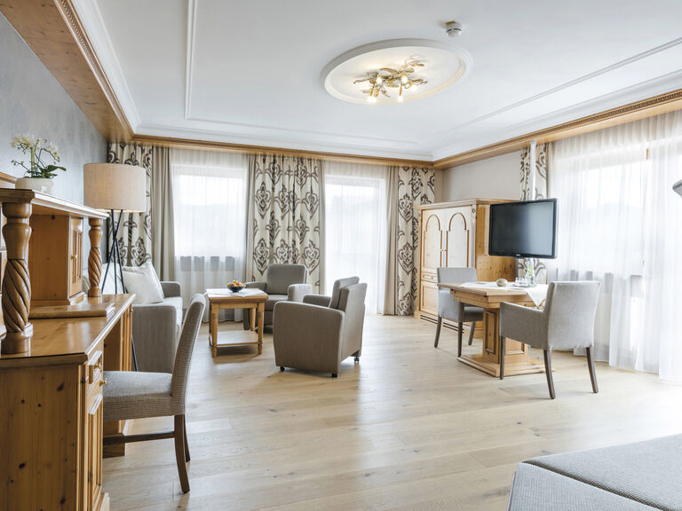 Gut ausgestattete Wohnzimmerecke in der 4-Sterne-Panoramasuite des Hotels Mooshof in Bodenmais mit modernem Interieur und Fernseher.