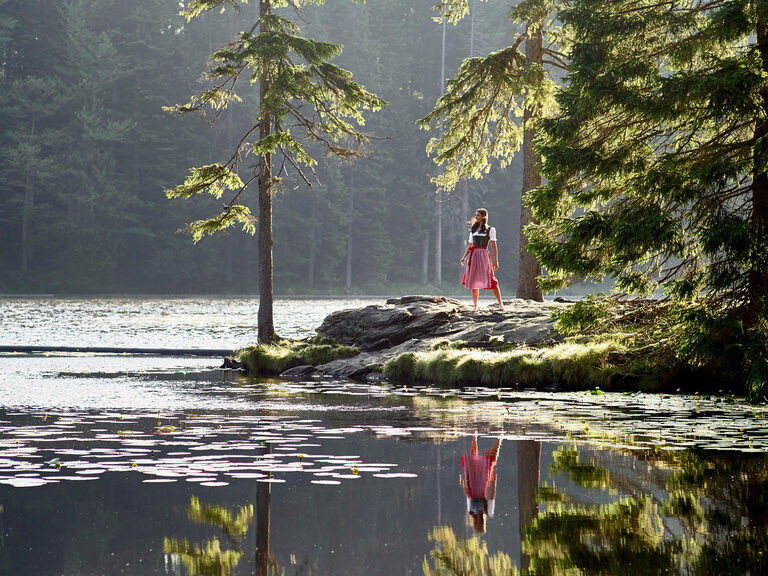 Eine Person joggt bei nebeligem Wetter an einem ruhigen See entlang.