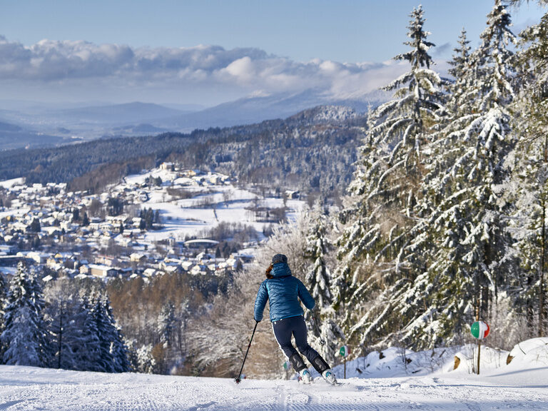 Eine Person fährt auf Skiern eine verschneite Piste hinunter.