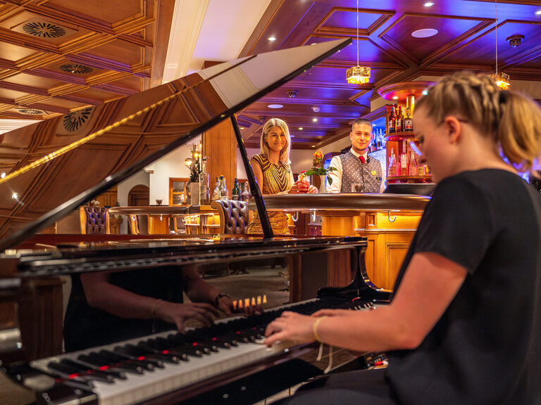Eine Pianistin liefert eine musikalische Darbietung in der Bar des Hotels Mooshof in Bayern.