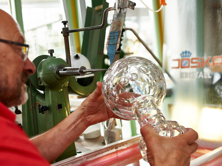 Ein Mann poliert eine selbstgeblasene Vase.