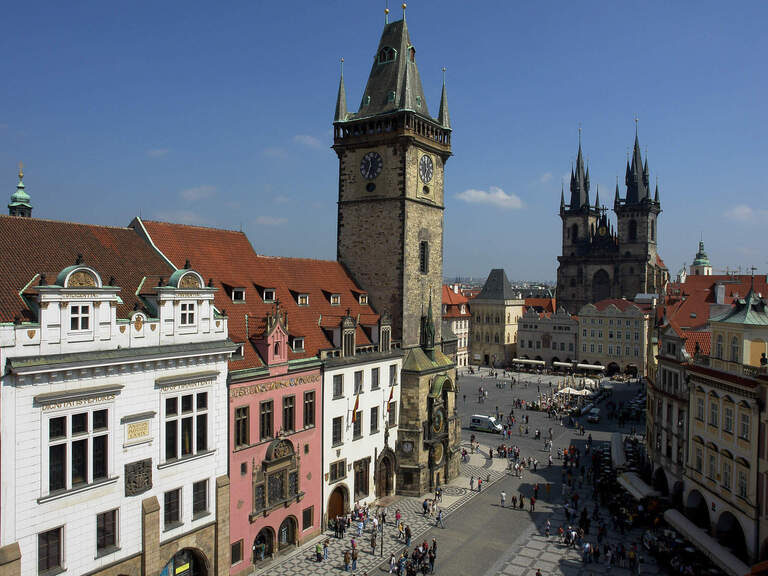 Der Stadtplatz Prags mit einem Uhrenturm und dem Dom im Hintergrund.