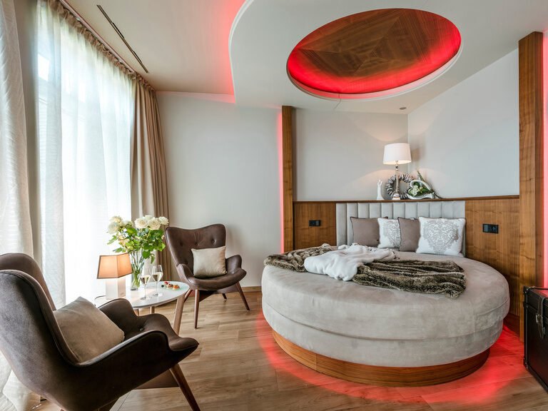 Der gemütliche Schlafbereich mit runden Bett und Stühlen in der Private Spa Suite des Wellnesshotels Mooshof im Bayerischen Wald.