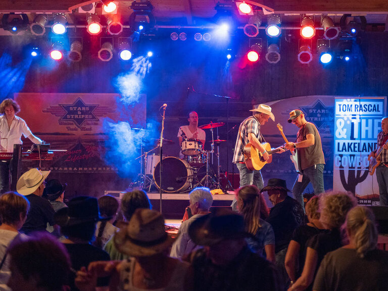 Eine musikalische Gruppe begeistert mit Country Musik auf der Bühne bei einem Konzert von Pullman City.