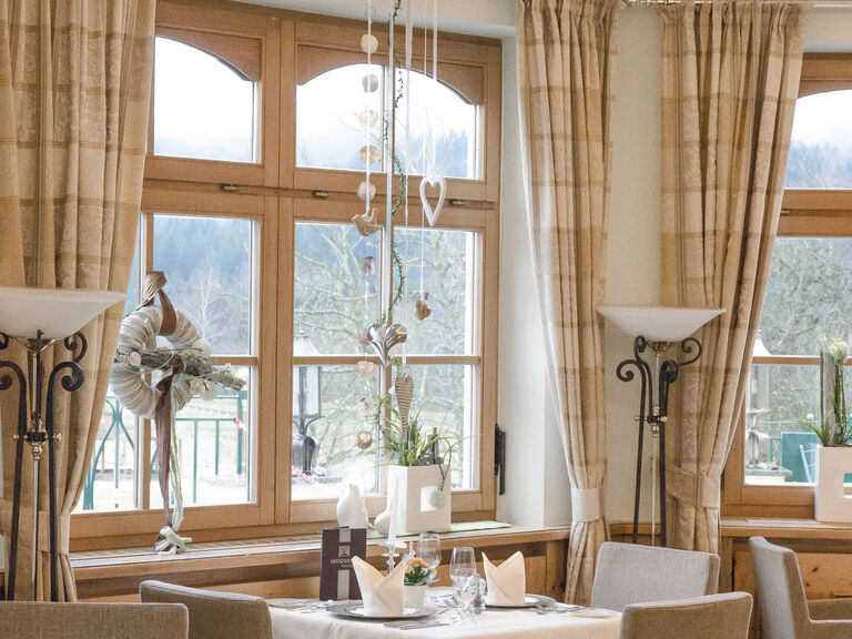 Eleganter Speisesaal des Restaurants Erkerlounge im Hotel Mooshof in Bodenmais mit mehreren Tischen und Stühlen lädt zum Verweilen ein.