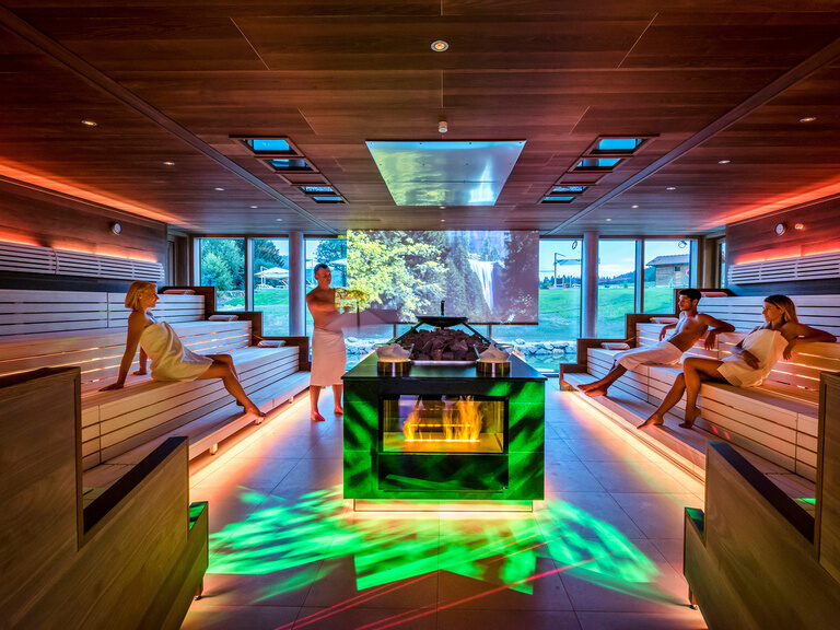 Eine Gruppe von Menschen sitzt in der Sauna im Wellness & SPA Resort Mooshof.