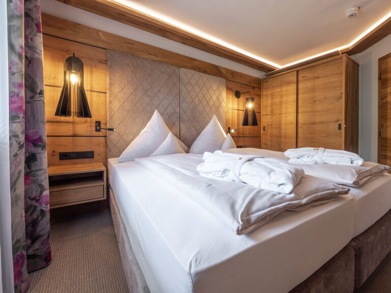 Einladendes großes luxuriöses Doppelbett mit weißen Laken und Kissen im Zimmer Typ 1 des Wellnesshotels Mooshof im Bayerischen Wald.