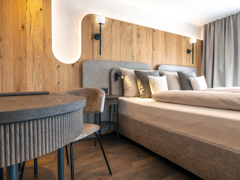 Ansprechend gestaltetes Schlafzimmer im Zimmer Typ 3 des Wellnesshotels Mooshof im Bayerischen Wald mit Doppelbett und einem Schreibtisch.