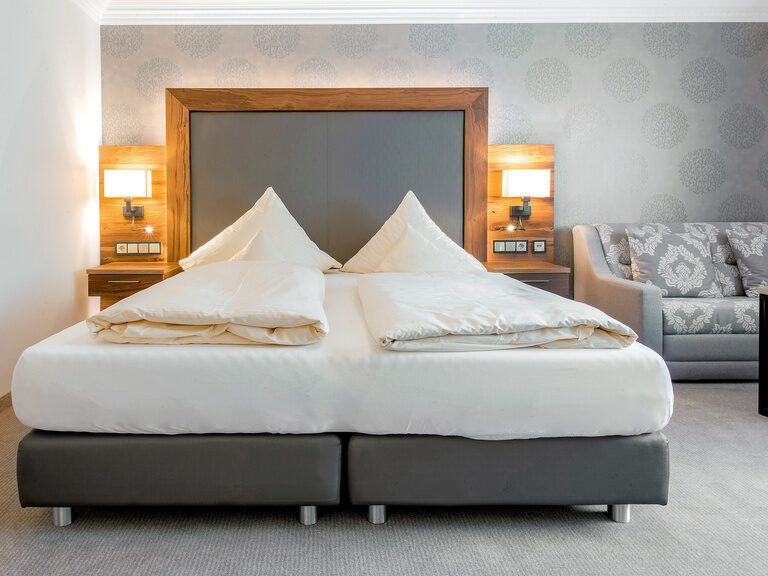 Das Hotelzimmer Typ 5 des Wellnesshotels Mooshof ist mit einem großen Bett und einer bequemen Couch geschmackvoll eingerichtet.
