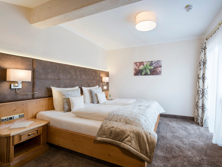 Hochwertige Möbel und moderne Beleuchtung schaffen eine einladende Atmosphäre in der Silberbergsuite des Wellnesshotels Mooshof in Bayern..