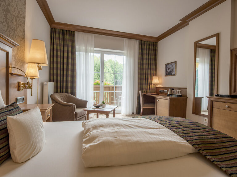 Großes Bett mit Flachbildfernseher und Ausblick auf dem Nordbalkon im Single-Suite Zimmer des Wellness & SPA Resort Mooshof im Bayerischer Wald.
