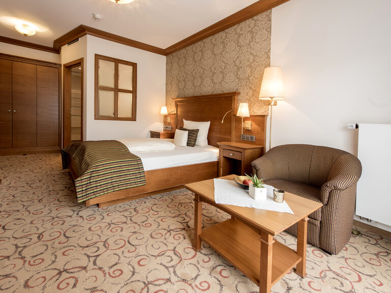 Komfortables Hotelzimmer in der Single-Suite des Wellnesshotels Mooshof in Bodenmais mit einem Bett und einer einladenden Sitzgelegenheit.