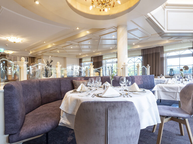 Tische mit feinem Tischgedeck in dem elegant gestalteten kulinarischen Esszimmer der Sonnenstube des Wellnesshotels Mooshof im Bayerischen Wald.
