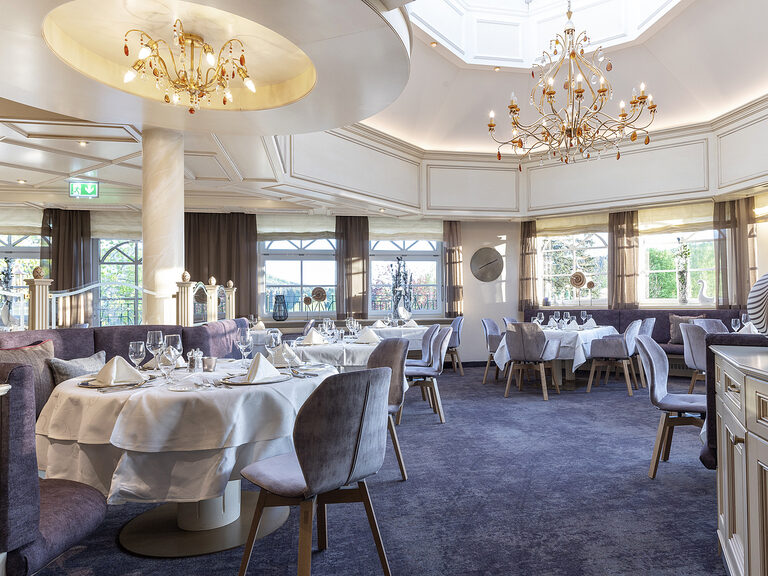 Das fein eingerichtete Sonnenstuben Restaurant im Hotel Mooshof, das mit glanzvollen Kronleuchtern beleuchtet ist.