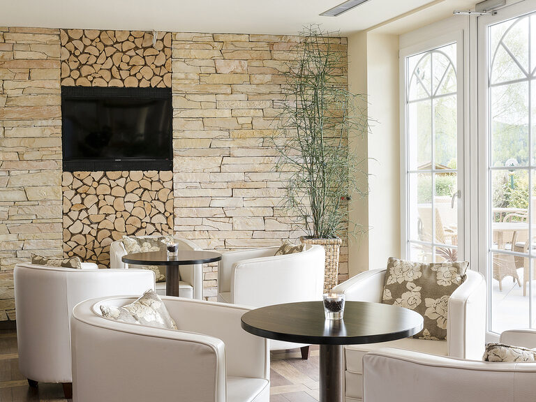 Komfortable Sessellandschaft mit Tischen zum Entspannen im Spa Bistro des Wellnesshotels Mooshof im Bayerischen Wald.