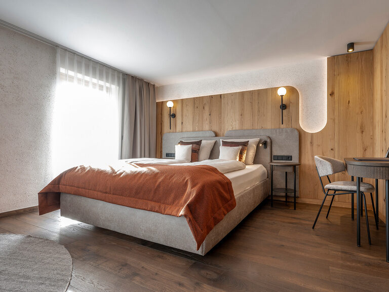 Das moderne Schlafzimmer in Zimmer Typ 3A des Hotels Mooshof in Bodenmais mit gemütlichem Bett und praktischem Schreibtisch.