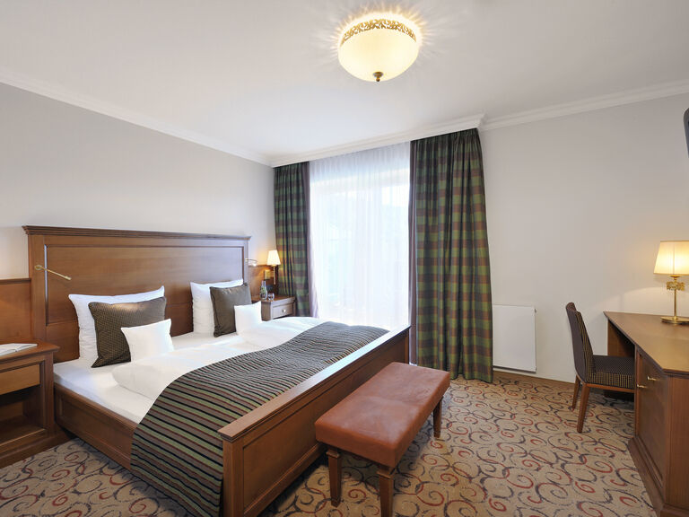 Einladendes Schlafzimmer mit hochwertigem Bett im Kirschholzdesign in der Traumblick Suite des Wellnesshotels Mooshof im Bayerischen Wald.