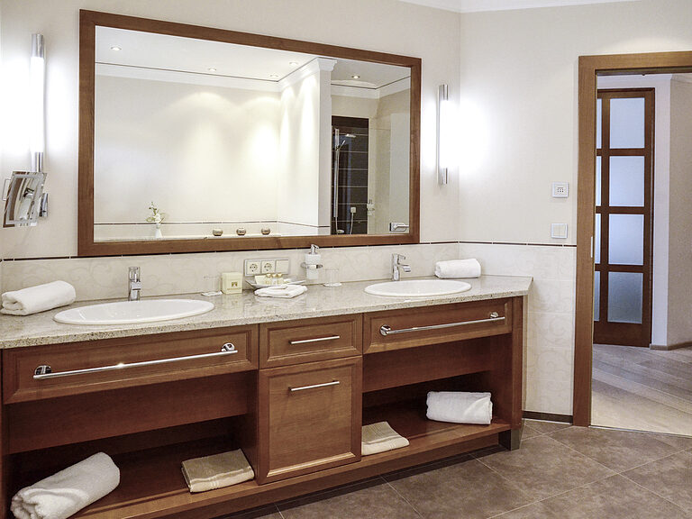 Zwei Waschbecken und ein großer Spiegel im Bad der Turmsuite Hochzell des Wellnesshotels Mooshof in Bayern.