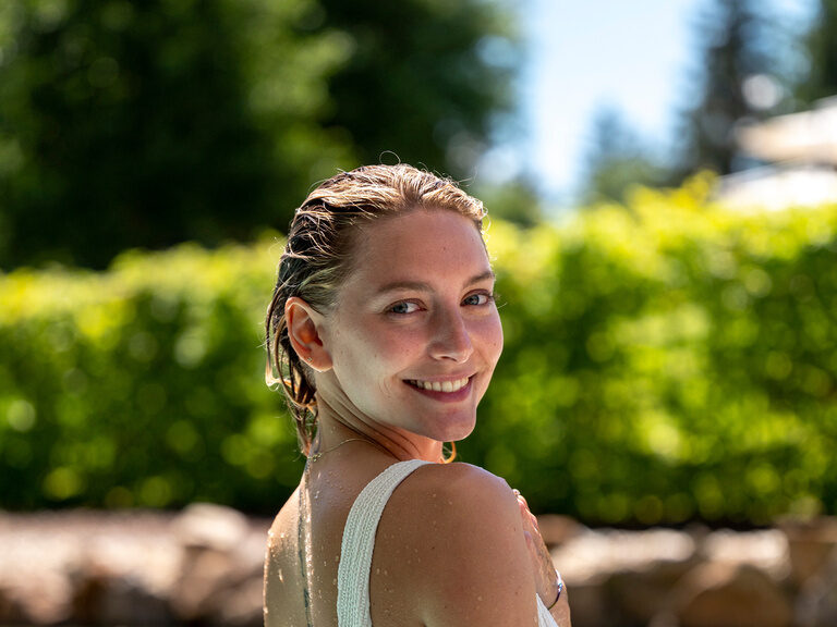 Im Wellnesshotel Mooshof in Bodenmais taucht eine Frau ins erfrischende Wasser des Aussenpools ein.