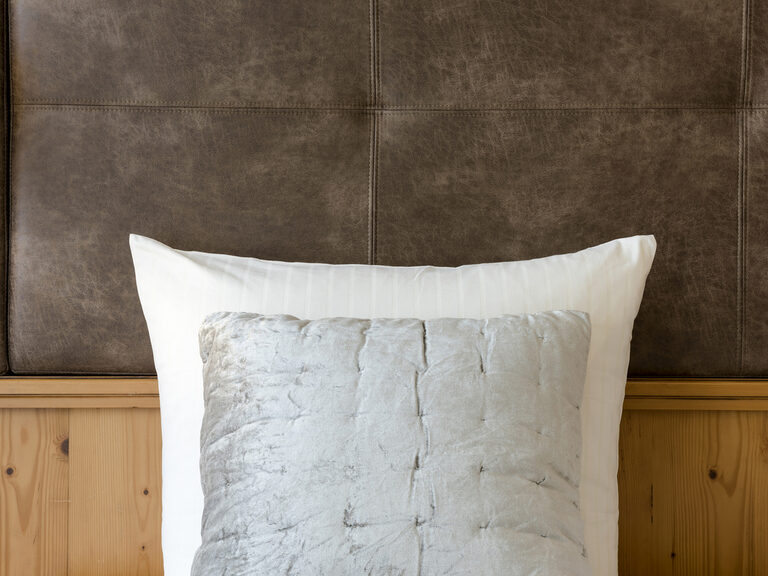 Ein flauschiges Kissen liegt auf der eleganten Bettwäsche im Schlafzimmer der Panoramasuite des Wellnesshotels Mooshof in Bodenmais.