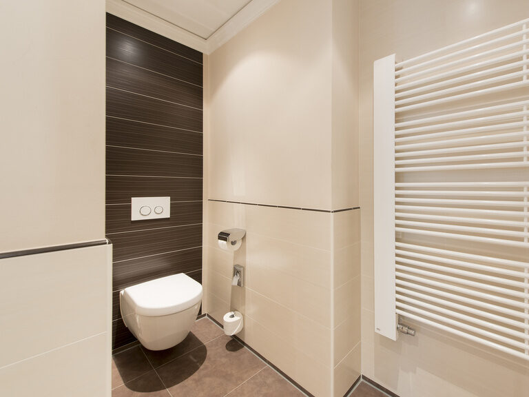 Das moderne Badezimmer der Hotel Mooshof Single-Suite im Bayerischen Wald mit einer weißen Toilette und schicken Fliesen.