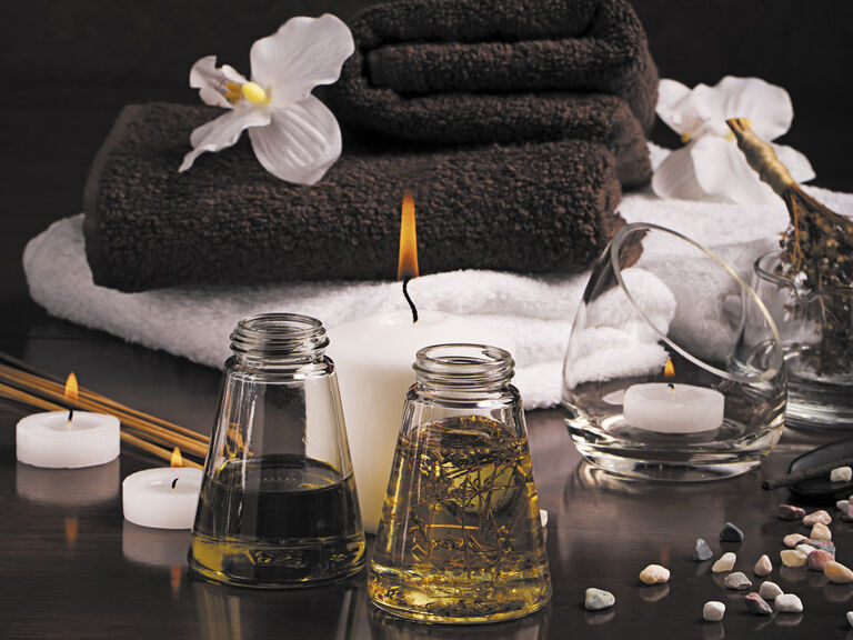 Ein Tisch mit Spaprodukten für Wellnessanwendungen, dekoriert mit Kerzen und gefalteten Handtüchern.