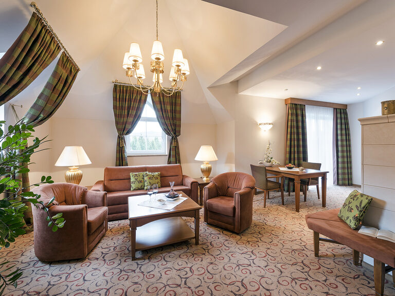 Gemütlicher Wohnraum in der Wellness & SPA Resort Mooshof Bergzauber Suite mit Sitzgelegenheit und Kamin.