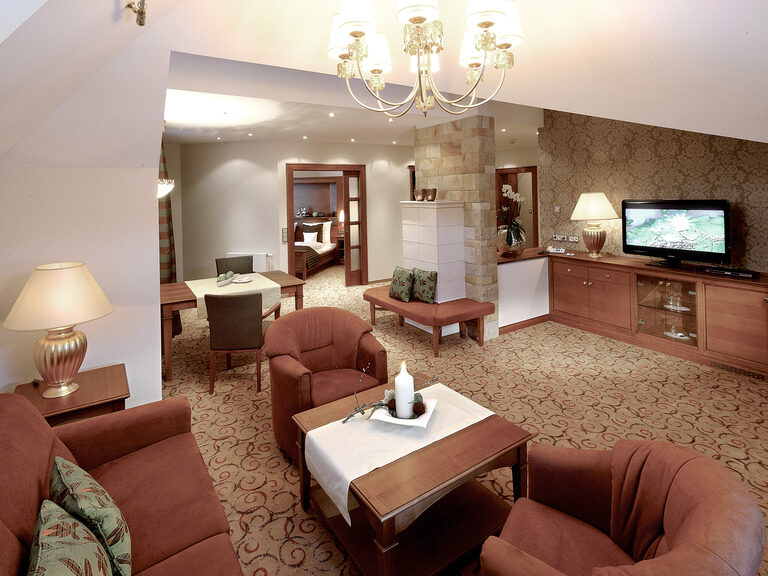 Warmes Ambiente in dem Wohnzimmer mit Kirschmöbeln der Wellnesssuite Bergzauber, perfekt für einen Wellnessaufenthalt im Hotel Mooshof in Bayern.