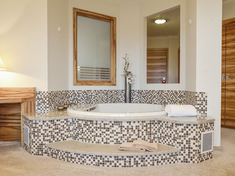 Modern freistehender runder Whirlpool mit Spiegel als Highlight in der Honeymoonsuite des Wellnesshotels Mooshof im Bayerischen Wald.