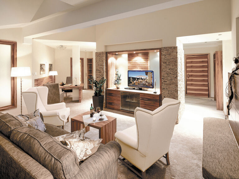 Das geschmackvoll eingerichtete Wohnzimmer in der Romantiksuite mit eleganter Möblierung und Flachbildfernsehr im Hotel Mooshof
